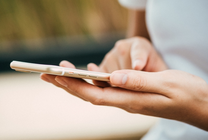 Frau hält Handy in der Hand und tippt etwas ein