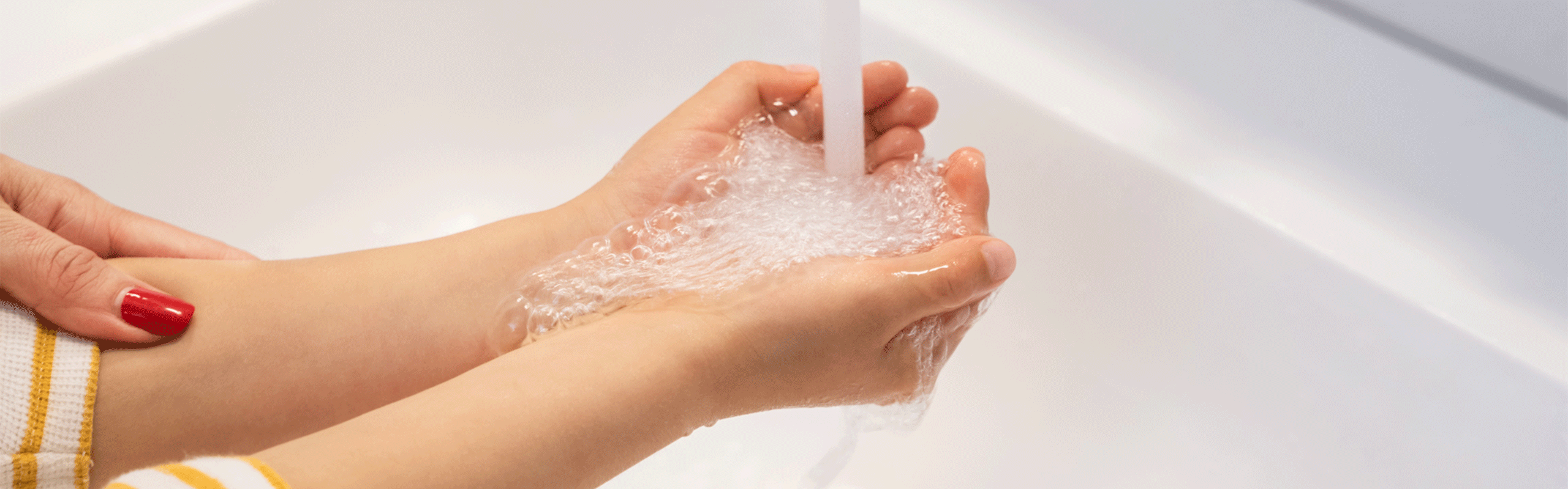 Kind hällt Hände unter Wasserstrahl im Waschbecken