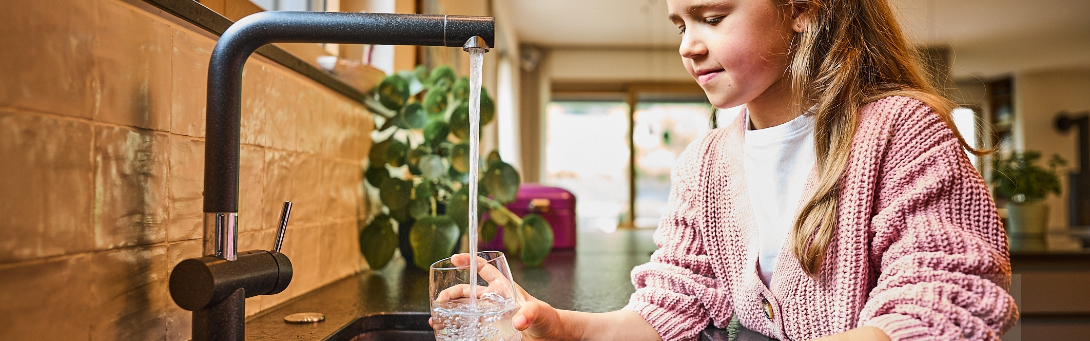 Mädchen am Wasserhahn trinkt Trinkwasser